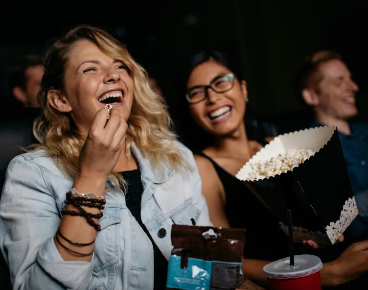 People laughing at a film with popcorn