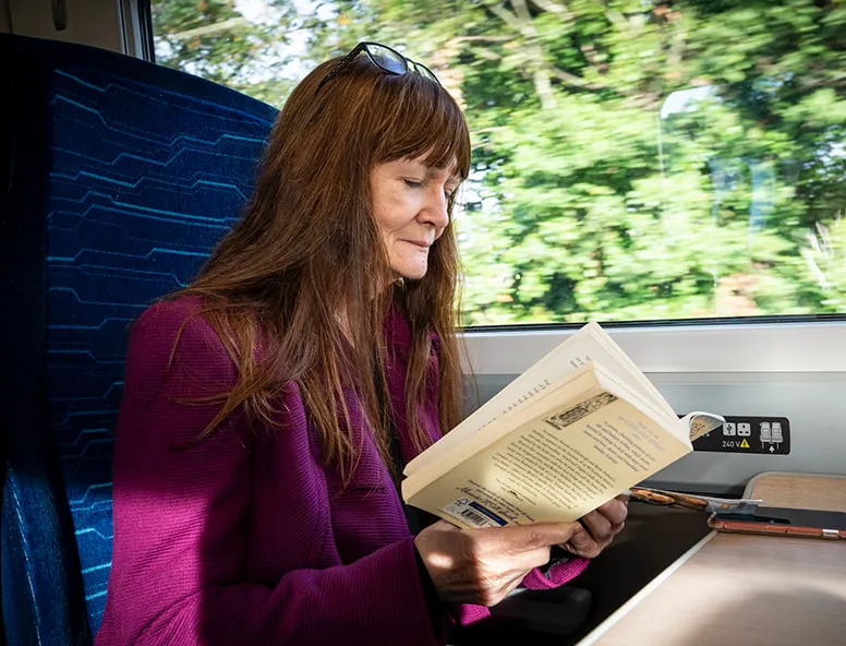 A person sat onboard a train reading a book