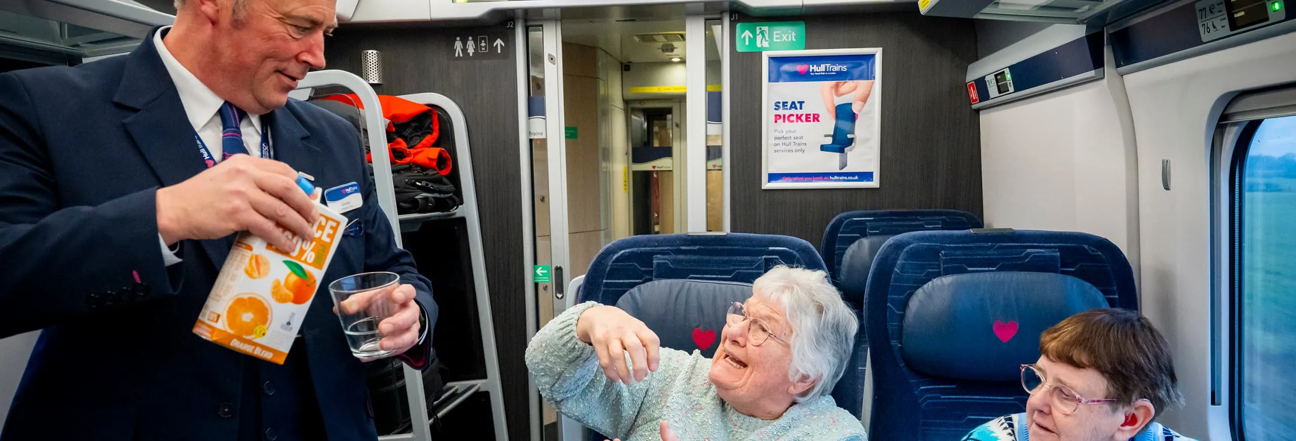 A photo of the Hull Trains onboard host serving cold drinks to two passengers